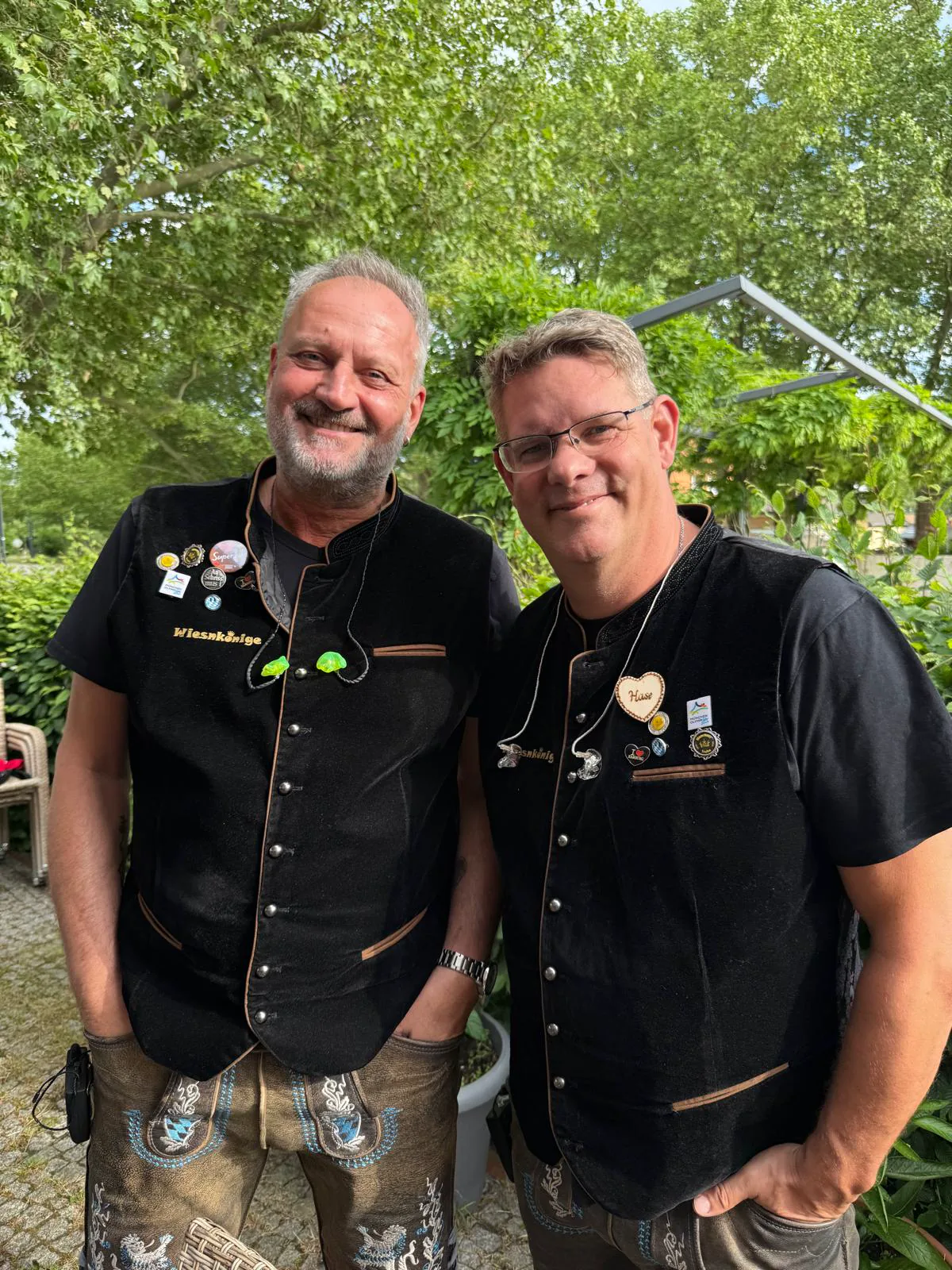 Zwei Musiker der Wiesnkönige in bestickten Westen und Lederhosen im Grünen