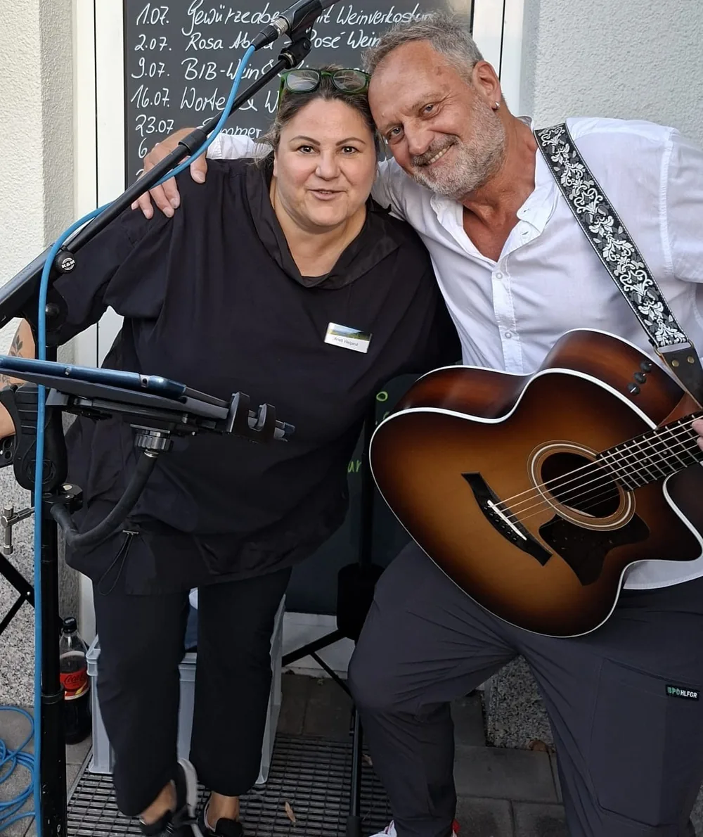 Michael Stern mit Akustikgitarre bei einem Auftritt vor einem Veranstaltungsort