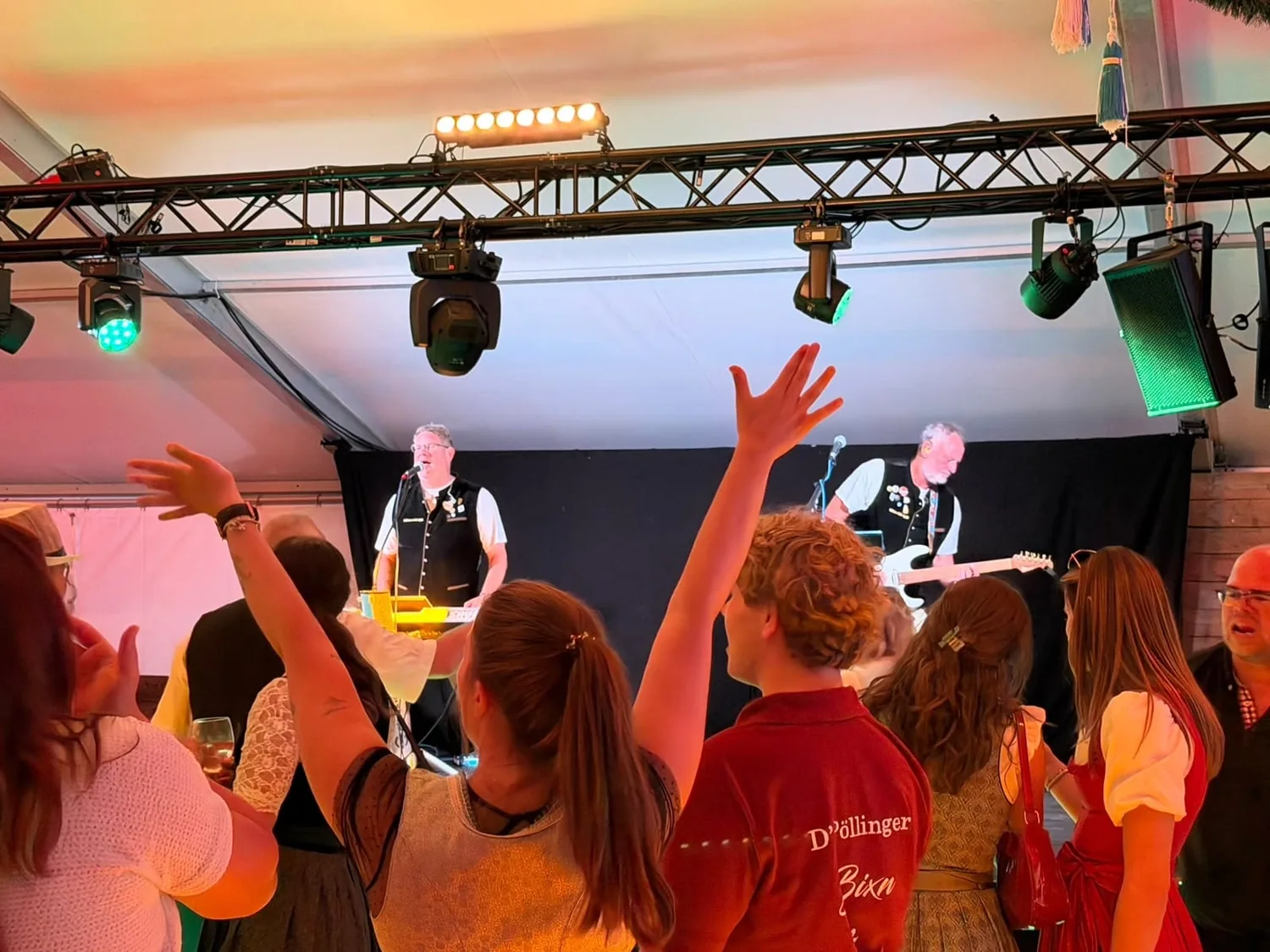 Feierndes Publikum mit erhobenen Händen vor der Bühne im Festzelt